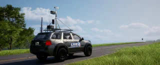 A liveried SUV with roof-mounted radar and weather instruments, parked on a road through open field